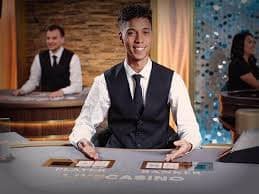 Dealer profesional berinteraksi dengan pemain di meja Caribbean Stud Poker imperialtoto